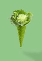 Green Ice cream cornet with cabbage flying on pastel green background. Vegetarian food. Creative food concept. Macro concept. Vegetarian concept. photo