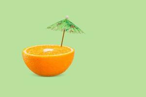 Tropical beach concept from orange fruits and sun umbrella. Minimal concept. Summer concept. photo