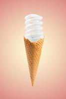 Compact fluorescent bulb in ice cream cone. Pink background. Creative summer concept photo