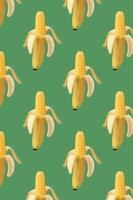 Pattern cob of corn in the peel of banana on green background. Food creative concept. Photo manipulation with banana. Art concept. Colorful fruit pattern. Tropical abstract background.