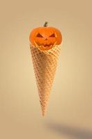 Halloween pumpkins with cone ice cream on pastel beige background. Creative idea minimal concept. Halloween sweet dessert. photo