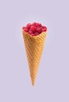 Ice cream cones with raspberries isolated on a blue background. Summer concept. photo