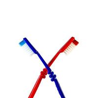 Two toothbrushes crossed on a white background. Blue and red toothbrushes photo