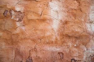 The texture of a red concrete wall with cracks and scratches can be used as a background photo