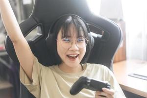 Una joven jugadora asiática adulta usa anteojos para jugar un juego en línea. foto