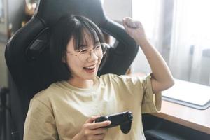 Nerd style young adult asian gamer woman wear eyeglasses and headphone play a online game photo