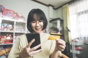 Young adult asian woman using smartphone and credit card make transaction via digital application photo
