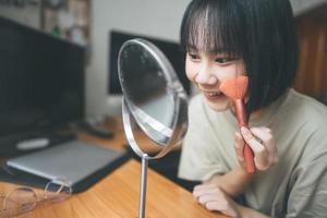 Young adult asian woman makeup and face skincare before mirror at home photo