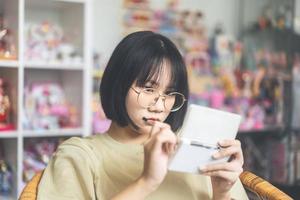 estilo nerd feliz joven adulto jugador asiático mujer usar anteojos jugar un juego en línea foto