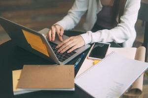 las mujeres adultas jóvenes estudian a mano y trabajan en línea en la mesa de un café con una computadora portátil. foto