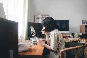 maquillaje de mujer asiática adulta joven y cuidado de la piel de la cara usando un teléfono móvil para transmitir creador de contenido en casa foto