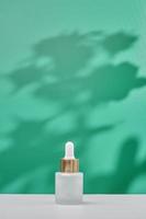 cosmetic product in tube, glass bottle, lotion, anti-aging moisturizer, facial essential oil or serum on green background with light shadow nature. Organic natural and Beauty skincare concept. photo