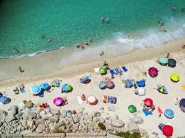 Italian beaches of Calabria seen from above, tourists seen rest under colorful umbrellas photo