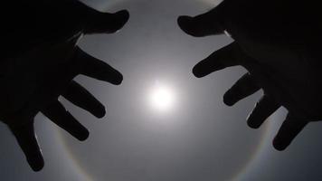 Aerial view of the sun with a circular rainbow surrounded by bright skies and white clouds with shadows of outstretched hands. Phenomenon, sun halo. Natural background in motion. video