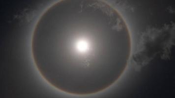 vue aérienne du soleil avec un arc-en-ciel circulaire entouré d'un ciel lumineux et de nuages blancs. phénomène, halo solaire. fond naturel en mouvement. drone tir soleil et nuages temps de mouvement video