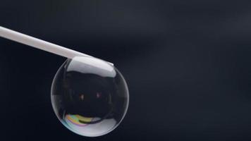 lindas bolhas de sabão são sopradas com um canudo em um background.abstract preto bolhas de sabão com reflexos coloridos. bolhas de sabão em fundo de movimento. video