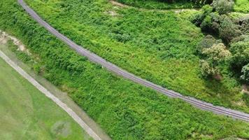 luchtfoto van een drone op een spoorlijn in een landelijk landschap met groen bos tijdens het regenseizoen. de drone vloog boven het bos en zag de spoorrails in de verte. video