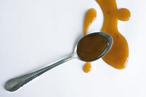 the drops of homemade sauce and a spoon on a white background photo