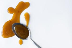 the drops of homemade sauce and a spoon on a white background photo