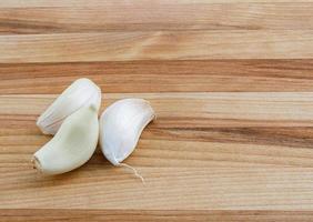 Three pieces of garlic lie on a wooden board. photo