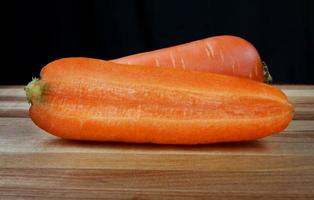 zanahorias y medias zanahorias en una tabla de cortar de madera. foto