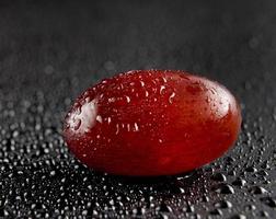 One grape berry on a dark background. Water drops. photo