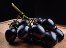 un pequeño racimo de uvas negras sobre una tabla de madera. foto