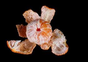 mandarina pelada con cáscara sobre fondo negro. aislar sobre un fondo negro. foto