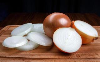 Whole bulb and chopped golden onions on a wooden background. photo