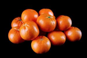 A bunch of fresh tangerines on a black background. photo