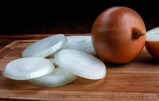 Whole bulb and chopped golden onions on a wooden background. photo