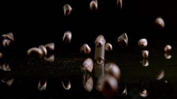 Coffee beans falling on a black mirror at the black background in slow motion. video