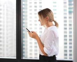 Portrait of a businesswoman using mobile phone in a bright office photo