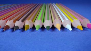 Colorful Pencils slider shot. This stock video features a collection of different color pencils laid out on a blue table.