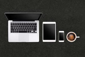 Laptop tablet smartphone  and coffee on black table background with text space and copy space photo