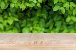 mesa de madera marrón sobre fondo de naturaleza verde abstracto bokeh - se puede utilizar para montar o mostrar sus productos foto