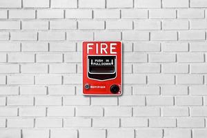 Fire alarm switch on white brick wall texture background photo