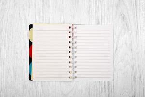 cuaderno abierto y un lápiz sobre una mesa de madera blanca, vista superior foto