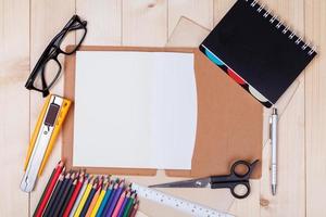 Workplace with colored pencils and supplies, notebook, eyeglass on wooden table photo