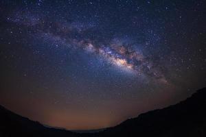 Landscape milky way galaxy with stars and silhouette of a standing happy man, Long exposure photograph, with grain. photo