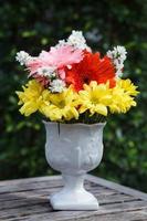 Bouquet of flowers in vase on wooden table photo