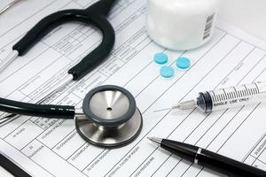 stethoscope syringe and pills on blank Patient information photo