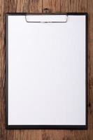 White paper on clipboard on wood background
