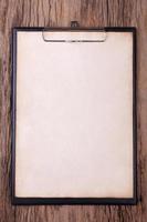 Old brown paper on clipboard on wood background photo