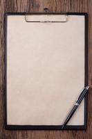Old blank paper on clipboard with space on wood background photo
