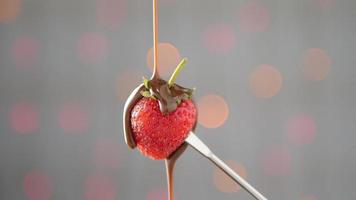 Pouring melt chocolate onto fresh strawberry over brink light bokeh background video