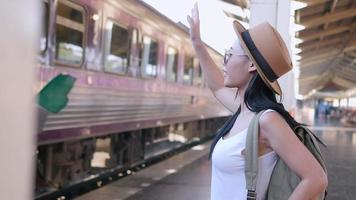 Woman traveler wave her hand to people in moving train - young traveler at train station concept video