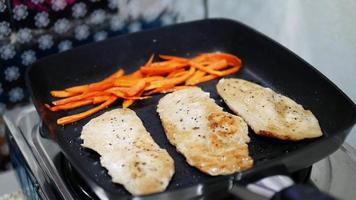 les gens font du steak de poulet dans la cuisine préparer un repas avec des légumes verts et orange - concept de préparation de nourriture maison video