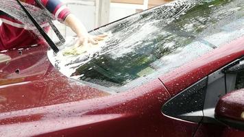 uomo che lava l'auto usando shampoo e acqua - concetto di pulizia dell'auto della gente di casa video