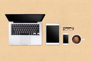 Laptop tablet smartphone  and coffee on brown background with text space and copy space photo